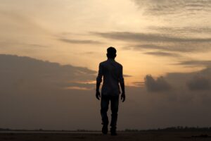 A solitary silhouette of a man walking during a serene sunset in India, reflecting solitude and introspection.